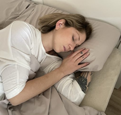Frau schläft im Bett mit Bollsen-Ohrstöpseln
